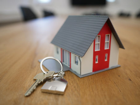 Miniature house model with a set of keys, symbolizing the concept of home ownership or real estate investment.